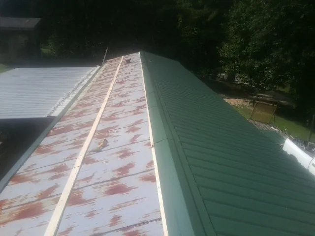 Old rusted panels beside newly installed green metal roofing — Wind Damage Roof Repair by Roofing Brothers in Middlesex