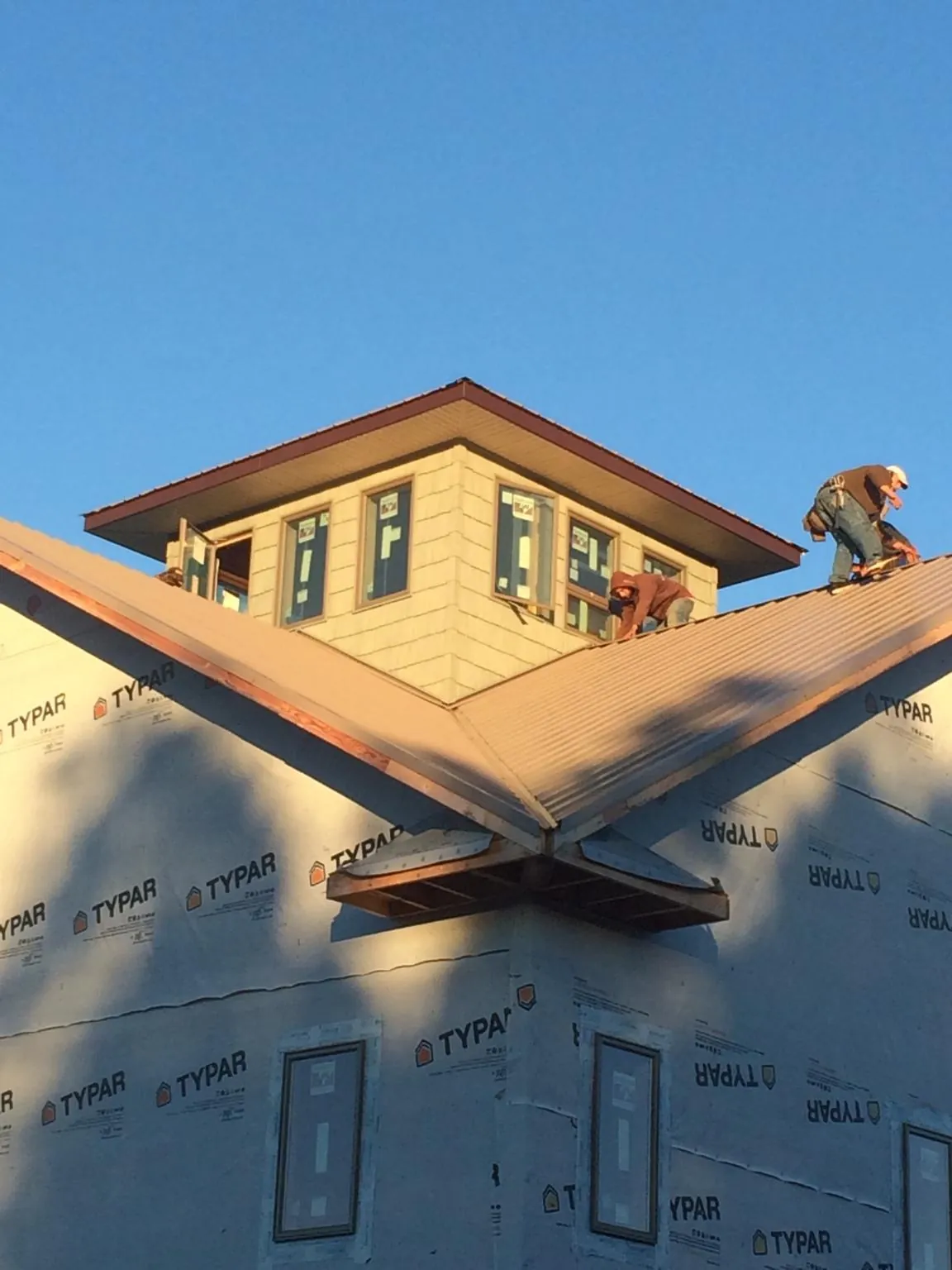 Roofers working around a rooftop cupola on a new metal roof at sunset — Roof Waterproofing in Middlesex by Roofing Brothers